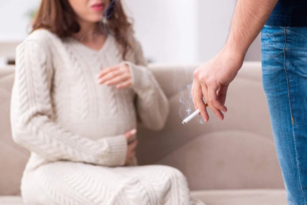 Eine schwangere Frau atmet Zigarettenrauch ein